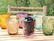Lade das Bild in den Galerie-Viewer, Bunte Wassergläser von Chic Antique aus der "Saint Émilion"-Serie mit Blattmuster. Die Gläser stehen auf einem Holztisch, im Hintergrund eine Blumenwiese.