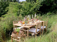 Lade das Bild in den Galerie-Viewer, Ein gedeckter Tisch aus Holz mit 4 Stühlen inmitten einer sommerlichen Blumenwiese.