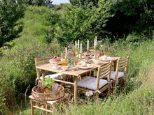 Lade das Bild in den Galerie-Viewer, Ein gedeckter Tisch aus Holz mit 4 Stühlen inmitten einer sommerlichen Blumenwiese.