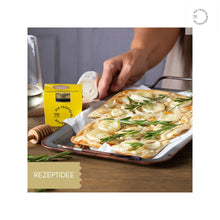 Lade das Bild in den Galerie-Viewer, Flammkuchen mit Ziegenkäse und Rosmarin, daneben steht ein Glas Trüffel Honigtöpfchen.