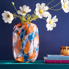 Lade das Bild in den Galerie-Viewer, Künstliche, weiße Cosmee in einer bunt gefleckten Vase vor blauem Hintergrund.