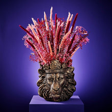 Lade das Bild in den Galerie-Viewer, Pflanzgefäß "Clarence" in Form eines goldenen Löwenkopfs mit Krone von Werns. In dem Übertopf ist ein rosanes Trockenblumengesteck, der Hintergrund ist blau.