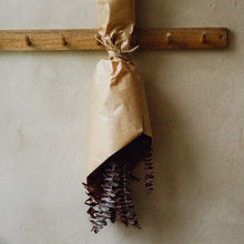 Lade das Bild in den Galerie-Viewer, Ein Bund getrockneter Eukalyptus in rot, eingewickelt in braunem Papier und aufgehangen.