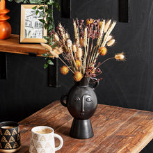Lade das Bild in den Galerie-Viewer, Sass & Belle Blumenvase in Kopf-Form mit Gesicht. Die Vase ist schwarz und ist beispielhaft mit einem Trockenblumen-Strauß präsentiert.