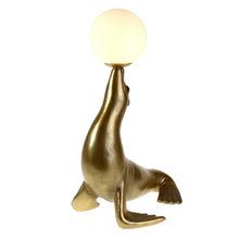 Lade das Bild in den Galerie-Viewer, Frontansicht von Lampe "Robbie" von Werner Voß in Form einer goldenen Robbe, die einen Ball auf der Schnauze balanciert. Der Ball ist dabei der Lampenschirm und aus satiniertem Glas.
