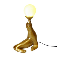 Lade das Bild in den Galerie-Viewer, Rückansicht von Lampe "Robbie" von Werner Voß in Form einer goldenen Robbe, die einen Ball auf der Schnauze balanciert. Der Ball ist dabei der Lampenschirm und aus satiniertem Glas.