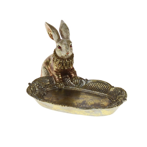 Kleines goldenes Tablett mit nostalgischen Verzierungen, über das sich ein Hase beugt, der ein Renaissance-Kostüm trägt.