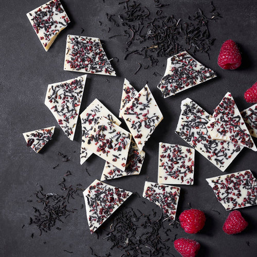 Weisse Schokolade mit einem Topping aus schwarzem Tee und getrockneten Himbeeren.